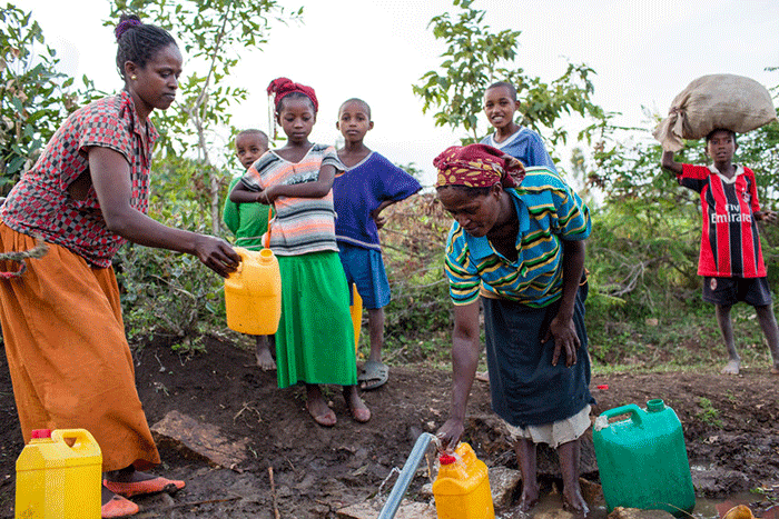 Women fetching water at a community source in Meteke Mele.