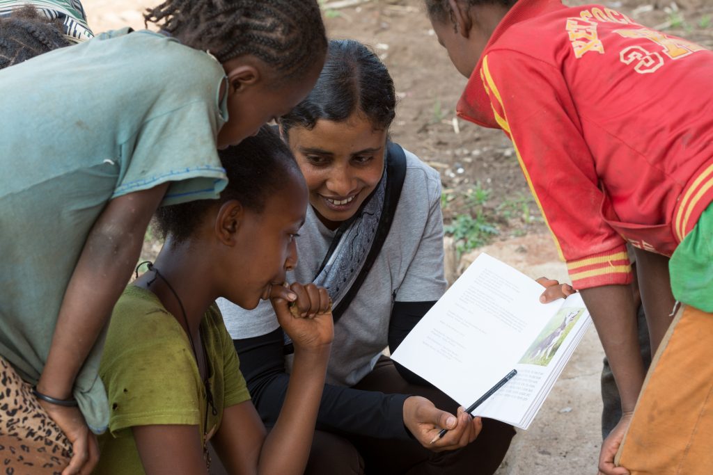 woman helping children read