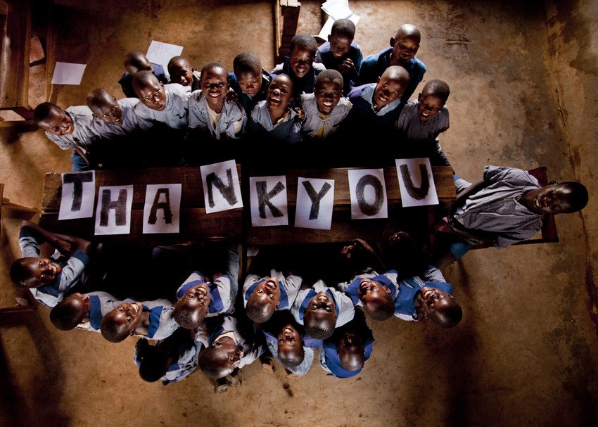 education program students holding a "thank you" sign and smiling