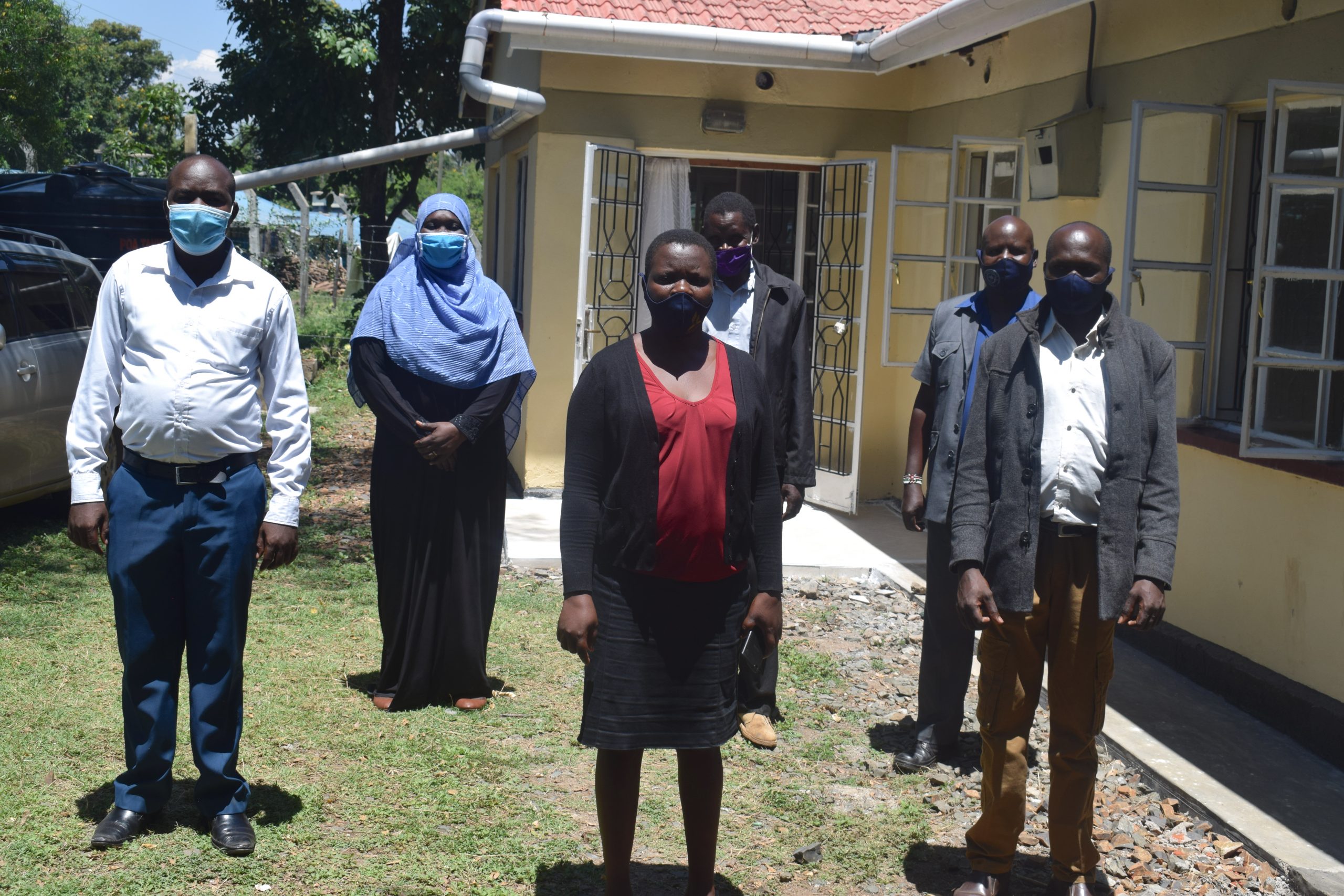 group of people standing outside together with masks while socially distanced 