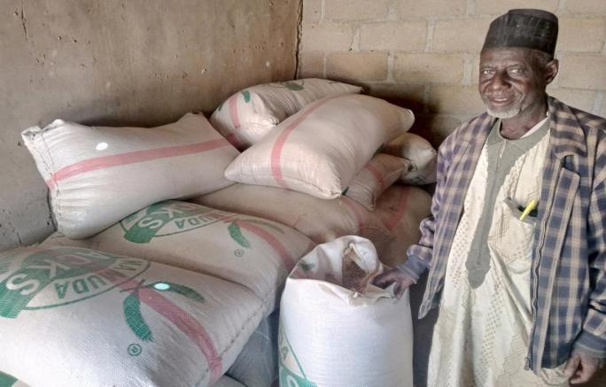 Farmer Mal Saleh next to bags of maize