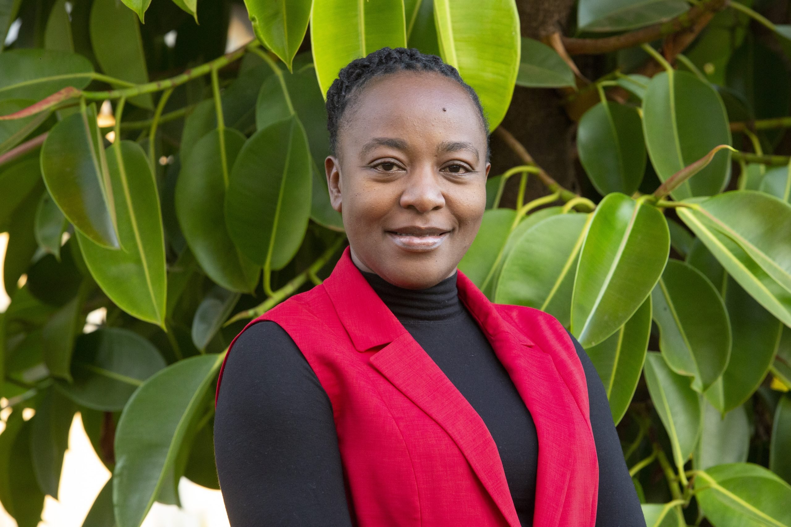 Pauline Wambeti stands in front of a green plant background