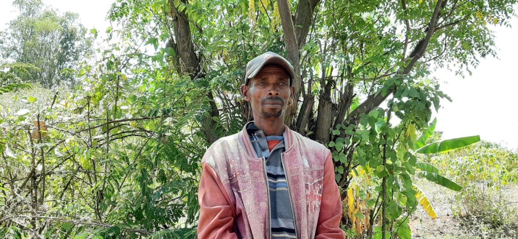 Nuru Ethiopia farmer - man standing in front of tree