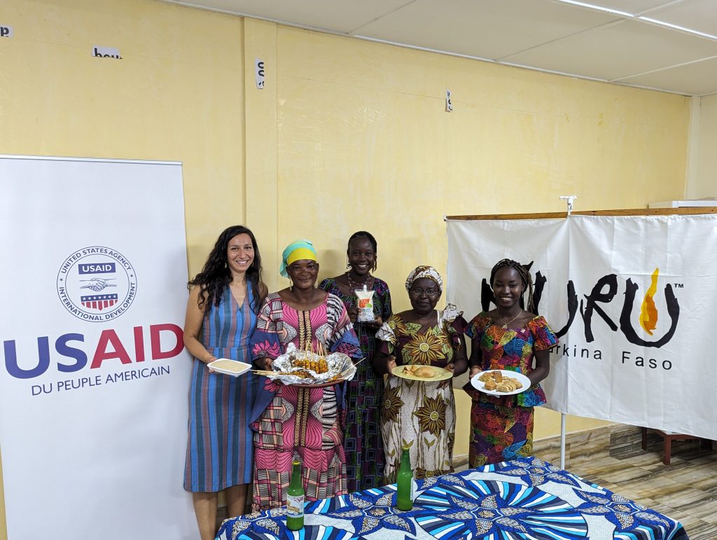 group of people standing together and holding food items while smiling at the camera