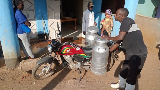 man delivering a cool of milk to a group of people outside a building