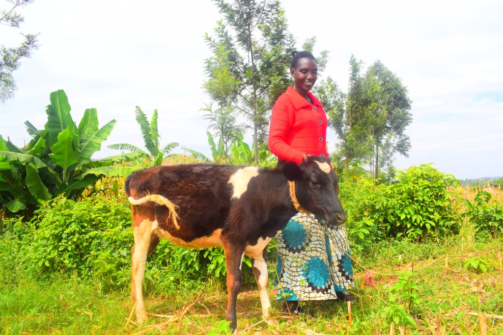 woman standing with a cow and smiling (Kenya)