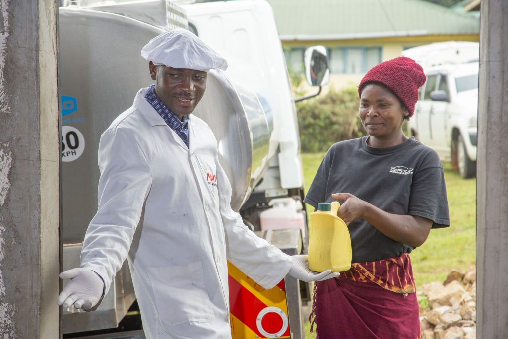 woman passing jug of milk to man 