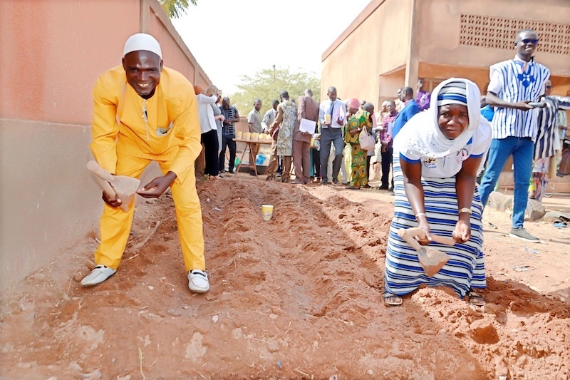 farmers in burkina faso working in dirt and smiling up at the camera