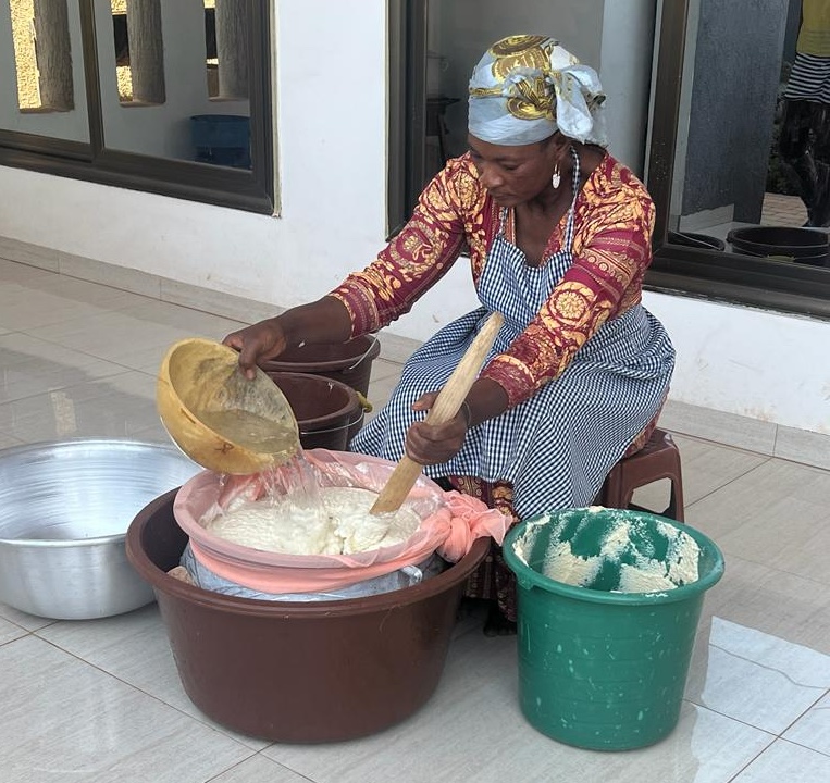 woman seated and processing soybean paste by pouring hot water over it to make soy milk 