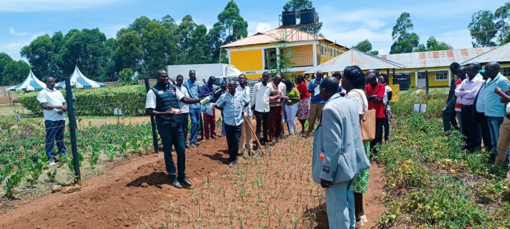 group of people from Baringo County standing outside in a field while one person presents information about crop production