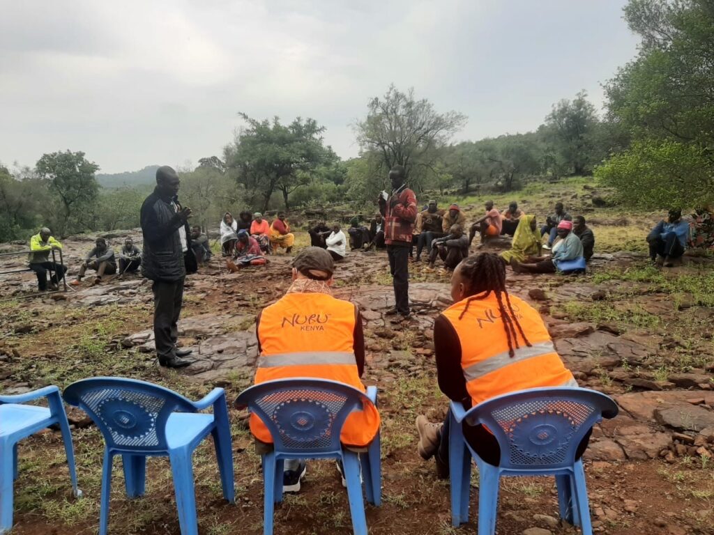 two people with Nuru vests sit facing a group of farmers in Baringo County 