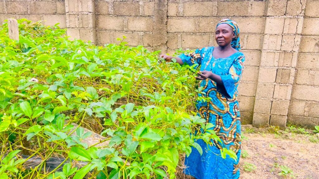 woman farmer stands outside in Nigeria with thriving garden