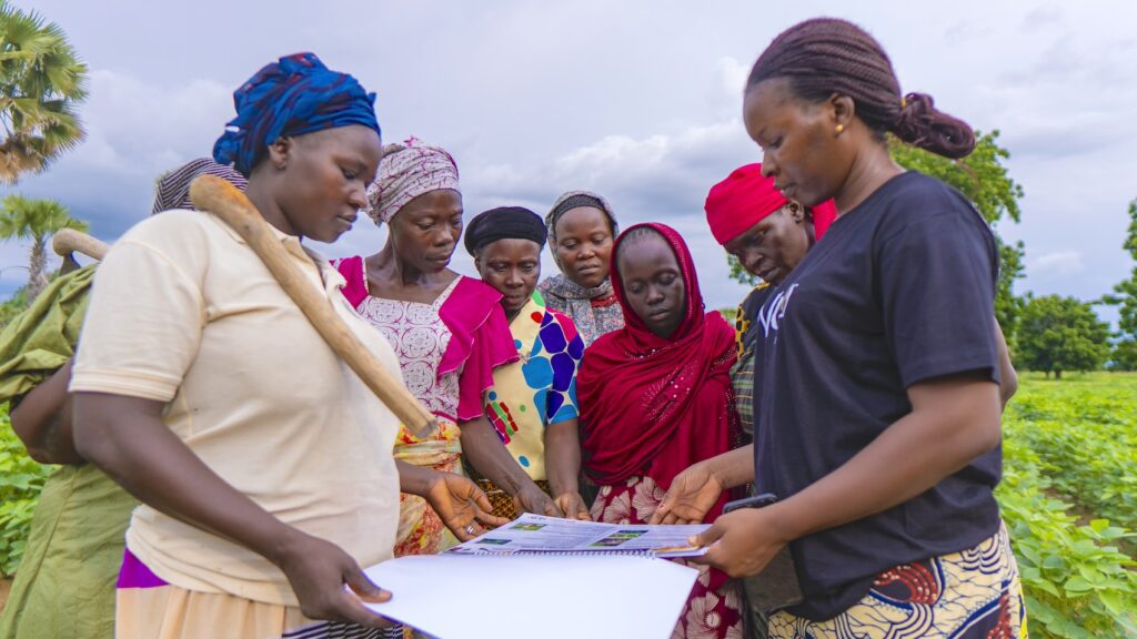 group of women standing in a field and looking at training materials together