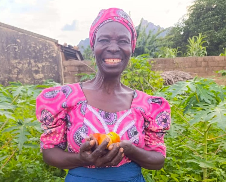 woman farmer in Nigeria smiling at the camera while holding produce