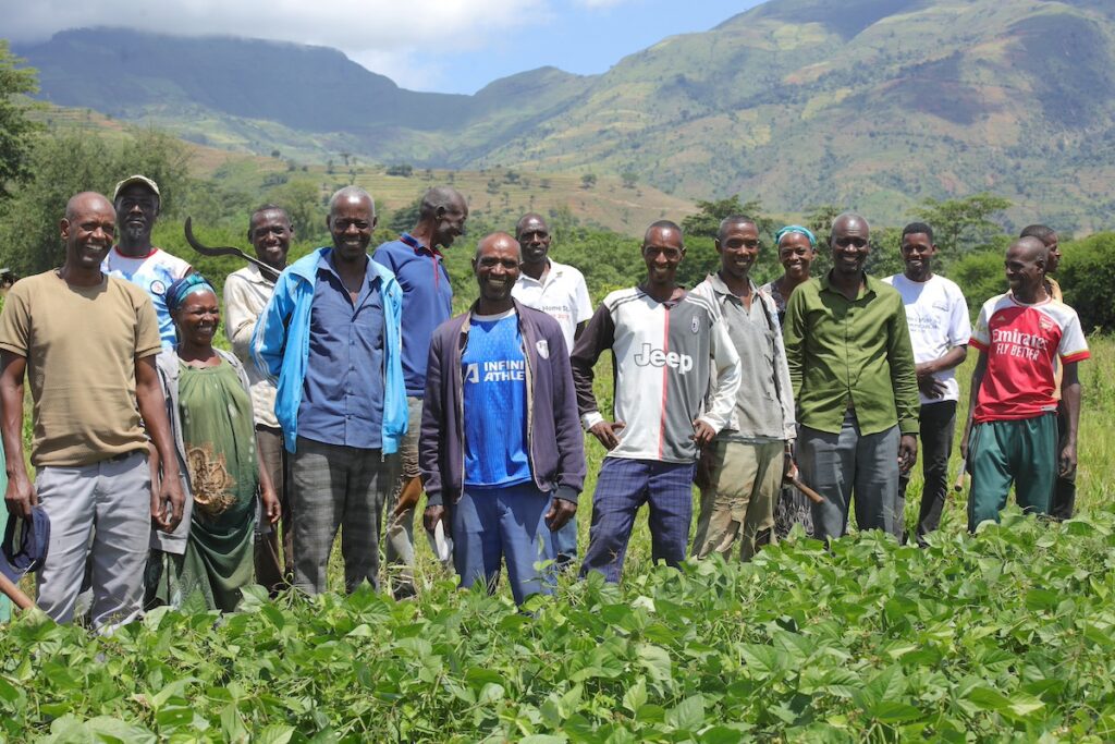 group of farmers smiling and laughing together in a field in Ethiopia