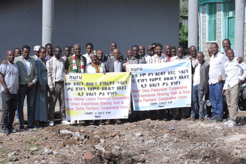 large group of people standing outside together and holding and event sign while smiling at the camera 