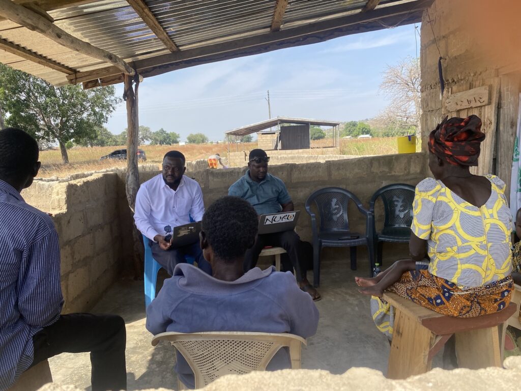 group of people meeting together in an outdoor location near a building in Ghana